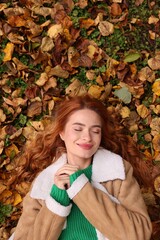 Wall Mural - Beautiful woman lying among autumn leaves outdoors, top view