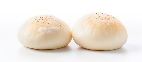 There are two steamed buns for siopao that can be seen on a plain white surface