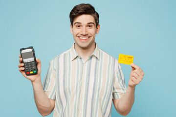 Poster - Young happy man he wears striped shirt casual clothes hold wireless modern bank payment terminal to process acquire credit card isolated on plain pastel light blue cyan background. Lifestyle concept.