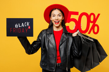 Wall Mural - Young woman wear casual clothes red hat hold shopping package bags cover face card sign with Black Friday written text inscription 50 percent isolated on plain yellow background. Sale buy day concept.