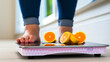 Woman's feet on scale with citrus slices, dieting concept.