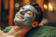 close up man at a spa relaxing with a green skin mask  in the face and with  closed eyes