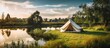 Luxurious morning glamping vibes with a white tent green grass and a blue sky near a pond