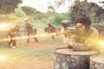 Wall Mural - Portrait of girl paintball player in mask who is aiming in opponents on paintball field