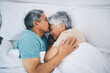 Top view, hug and senior couple in bed, love and sleeping with retirement, wake up or happiness with a kiss. Romance, old man or elderly woman embrace, bedroom or holiday with marriage or loving