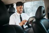 Fototapeta  - Business man, tablet and travel in car for online search, trading data and reading stock market information. Indian trader scroll on digital technology, financial website or driving in taxi transport