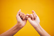 © Charlize D/peopleimages.com - People, hands and pinky promise in studio with trust, help or hope for reconciliation on yellow background. Finger, emoji and deal by friends with secret, gesture and support expression or solidarity