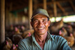 A smiling asian male chicken farmer stands with his arms folded in the poultry shed