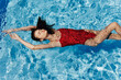 © SHOTPRIME STUDIO - Young woman in the pool in a red swimsuit with a beautiful smile lying on the water and swimming in the sun swimming in the pool, the concept of relaxing on vacation.