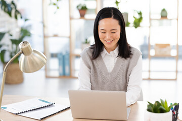 Poster - Asian woman, typing and laptop at startup with smile, planning and focus seo management. Young executive, social media content manager and computer in office for schedule, analysis and networking