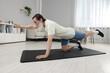 © New Africa - Senior man in sportswear doing exercises on fitness mat at home