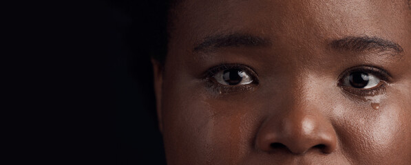 Black woman, eyes and mental health, crying with depression and crisis with abuse on dark background. Sad, portrait and anxiety, depressed female person with face on banner and grief in studio