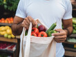 A person holds an eco shopping bag to buy fruit at a farmers market