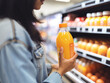 A woman buys organic orange juice at a supermarket