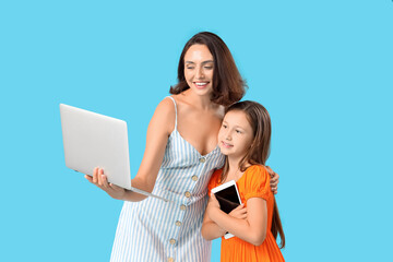 Wall Mural - Mother and daughter with laptop and tablet computer on blue background
