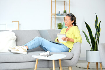 Sticker - Mature woman with laptop and notebook at home