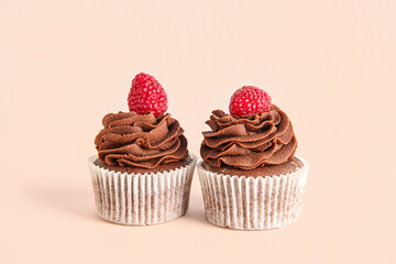 Wall Mural - Tasty chocolate cupcakes with raspberries on beige background