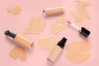 Bottles of makeup foundation with samples on pink background