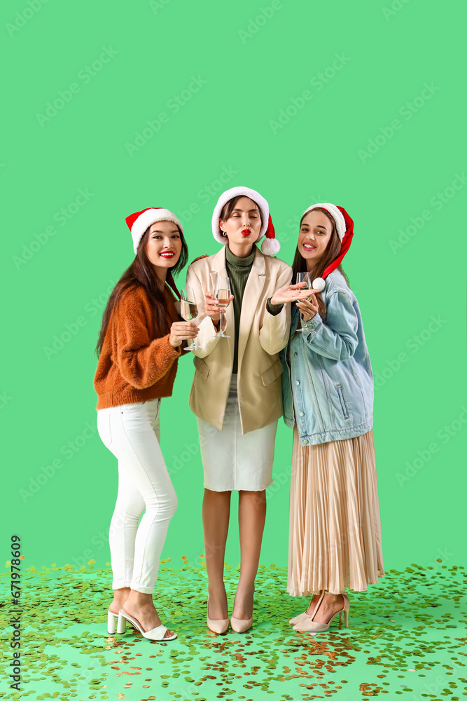 Female friends with champagne on green background. New Year celebration