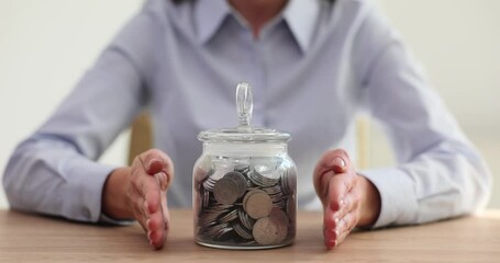 Wall Mural - Woman insurance agent guards money jar with coins closeup