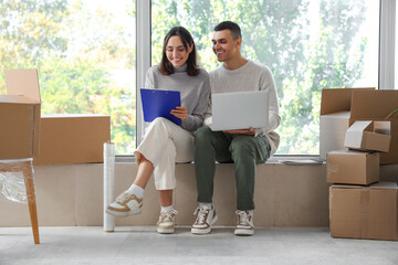 Poster - Happy young couple with laptop and clipboard in room on moving day