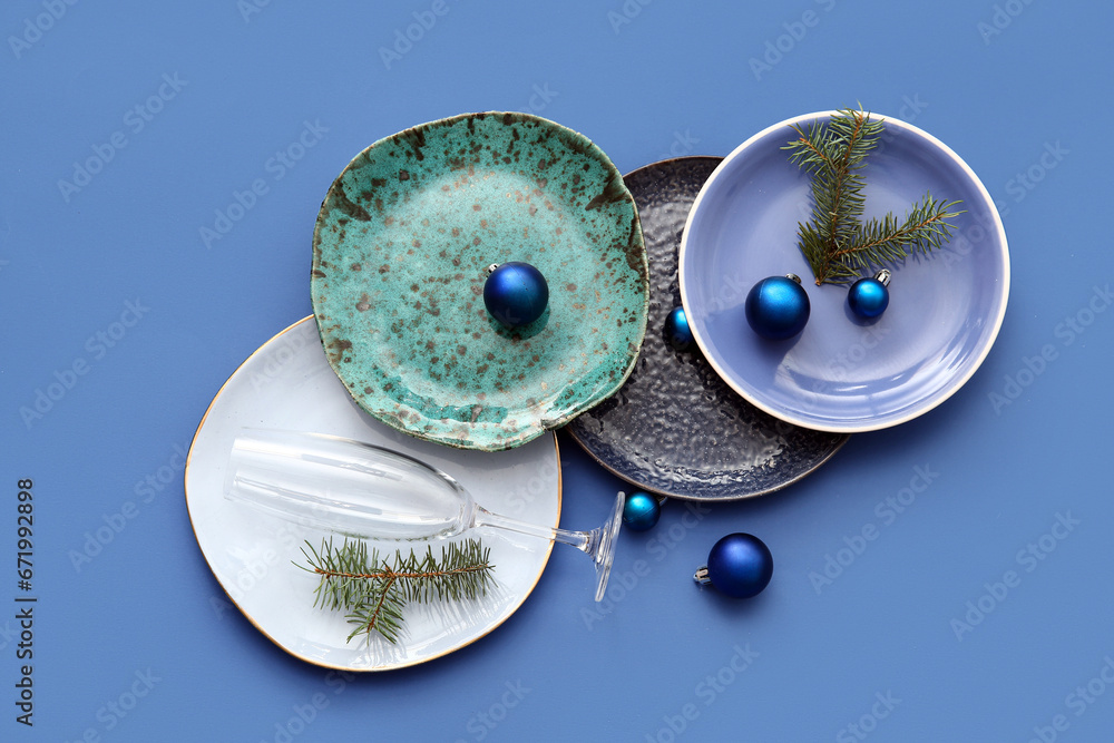 Beautiful table setting with Christmas balls and fir branches on blue background