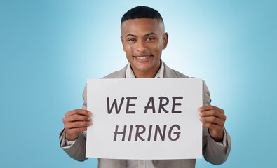 Canvas Print - Portrait, happy or businessman with we are hiring sign, work opportunity or vacancy advertising in studio. Smile, poster or manager with board text for job search or recruitment on blue background