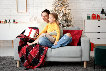 Canvas Print - Young mother giving her little daughter Christmas gift at home