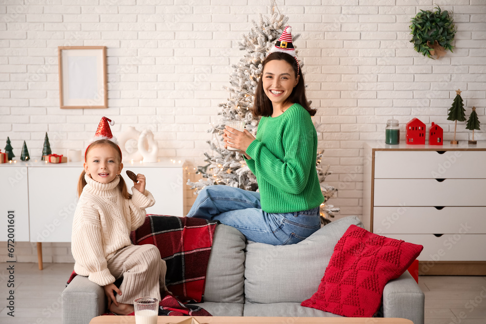 Happy mother and her little daughter drinking milk and eating cookie at home on Christmas eve