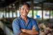 A smiling asian male pig farmer stands with his arms folded in the poultry shed ,generative ai