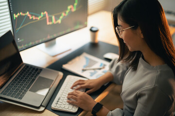 Wall Mural - Asian Business Woman is checking Bitcoin or stock market price chart on the digital exchange on a laptop monitor computer, cryptocurrency future price action prediction. Trading Stock Bitcoin ETF.