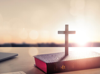 Wall Mural - silhouette wooden cross on holy bible sunset background