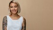 Smiling blond pretty smiling girl beauty female gen z model with short blonde hair beautiful face healthy skin and tattoo looking at camera wearing white top isolated at beige background