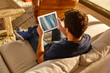 © h368k742 - Young man watching a tablet on a couch. Home working