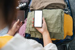 © Natee Meepian - Cheerful woman using mobile phone blank white screen display frameless modern design while pack clothes a suitcase ready for travel