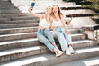 Two young beautiful smiling hipster female in trendy summer white top and jeans clothes. Carefree women posing in the street. Positive models having fun outdoors. Cheerful and happy. Take selfie