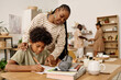 © AnnaStills - Mother controlling son doing homework at kitchen table