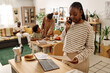 © AnnaStills - Serious Black woman checking reports when calling coworker, her kids doing homework in background