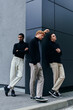 © LIGHTFIELD STUDIOS - thoughtful multiracial men in black turtlenecks posing together with wall on background, fashion