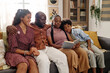 © AnnaStills - Hugging Black family sitting on couch and reading book about Martin Luther King Jr