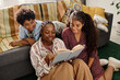 © AnnaStills - Smiling mother reading her kids about Civil Rights Movement