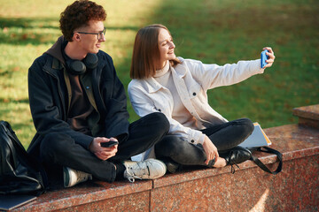 Wall Mural - Taking a selfie. Two young students are together outdoors
