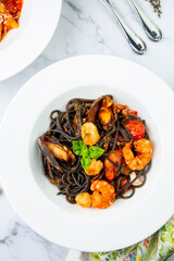 Wall Mural - black noodles with mussels, shrimp, tomatoes and herbs side view