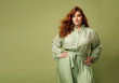 confident and calm beautiful happy red hair woman plus size model posing on green background