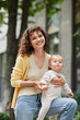 © LIGHTFIELD STUDIOS - portrait of smiling and curly woman with cute toddler daughter on urban street, happy motherhood