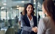 © .shock - Two businesswomen shake hands in a modern office, sealing a successful deal with smiles and professionalism