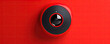 Detail on modern doorbell with mounted video camera on red background.
