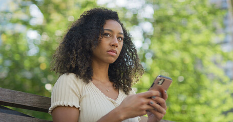 Poster - Young black woman using smartphone at a park