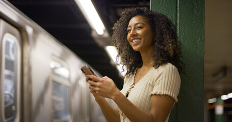 Poster - Young black woman using smartphone at a subway platform