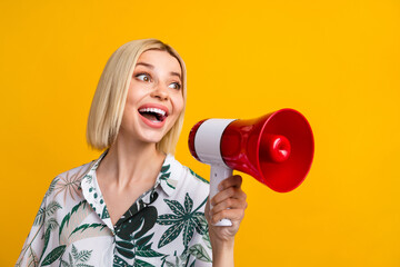 Photo portrait of pretty young girl hold megaphone announce sale wear trendy leaves print outfit isolated on yellow color background